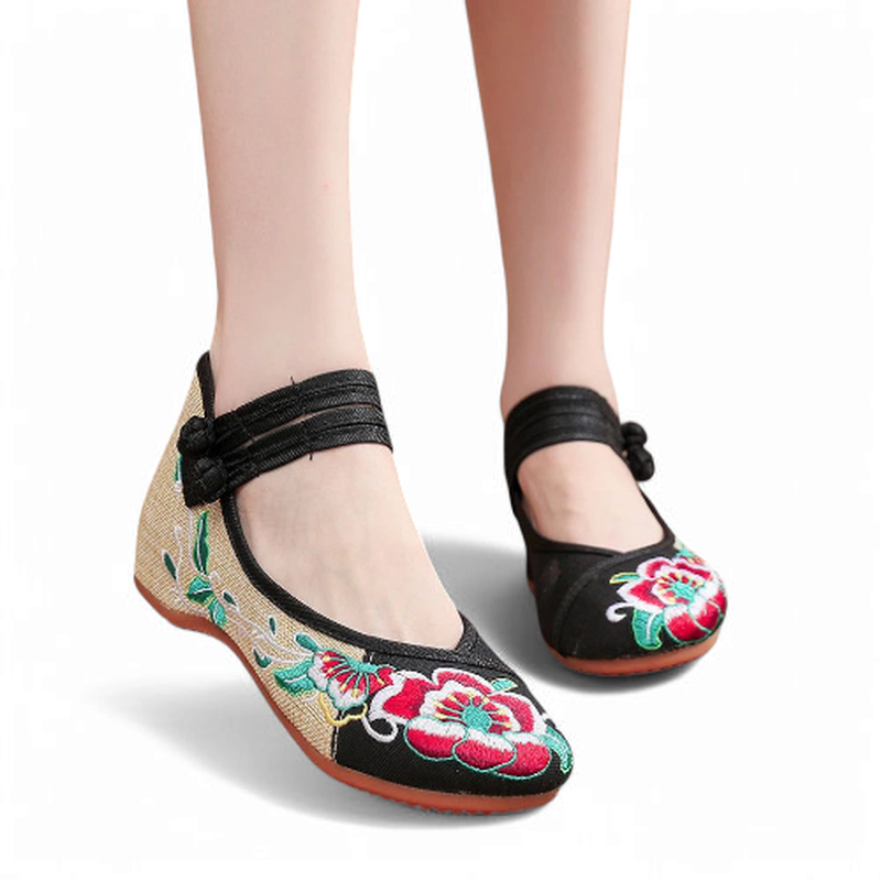 Front angle view of black and beige canvas Mary Jane flats with wide ankle strap and floral embroidery.