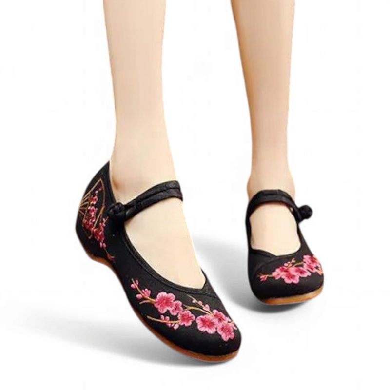 Front angle view of black Mary Jane flats with pink floral embroidery and fabric button strap.