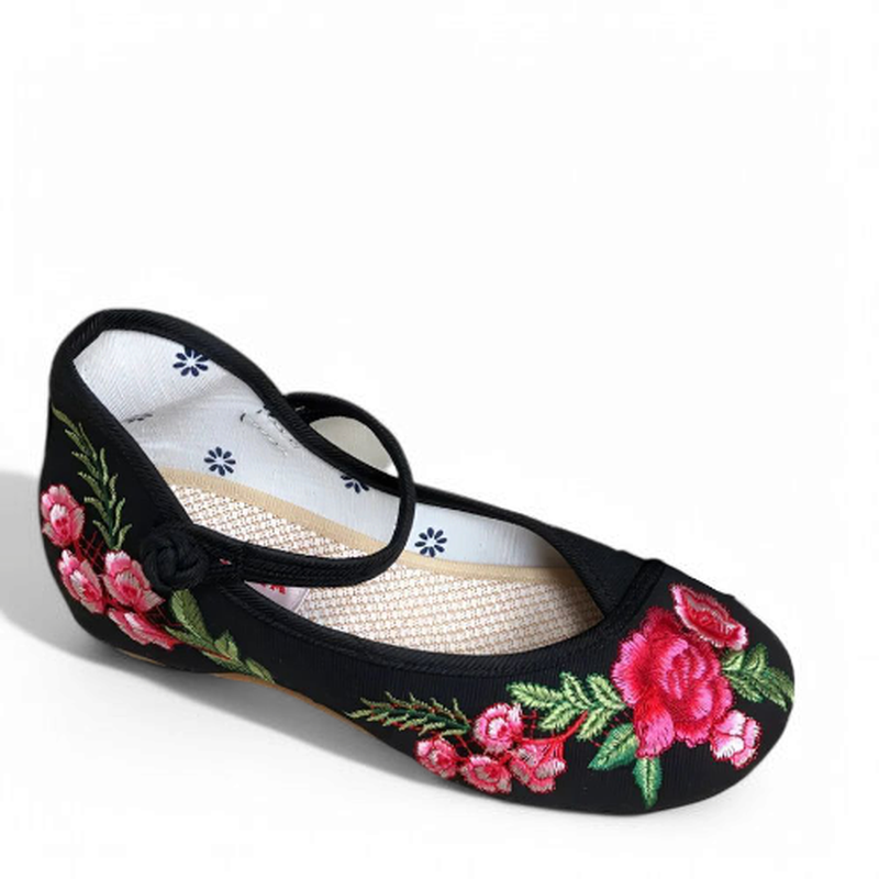 Three-quarter side view of single black embroidered Mary Jane with fabric strap.