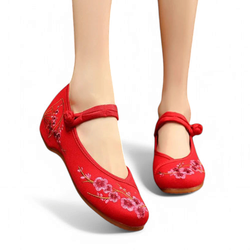 Front angle view of red canvas Mary Jane flats with cherry-blossom embroidery and a fabric knot strap.