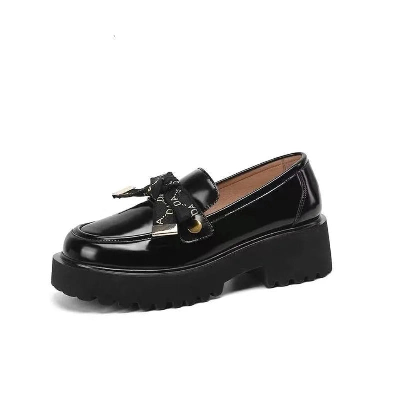 Glossy black loafer with thick platform and logo ribbon on white background.