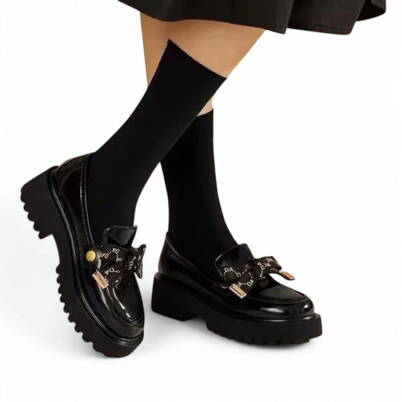 Side shot highlighting the raised sole and logo bow beneath black socks.