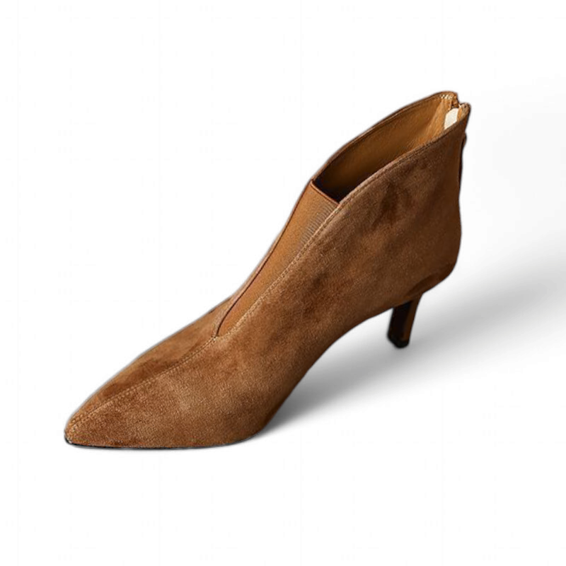 Brown suede boot tilted on white surface, pointed front in focus.

