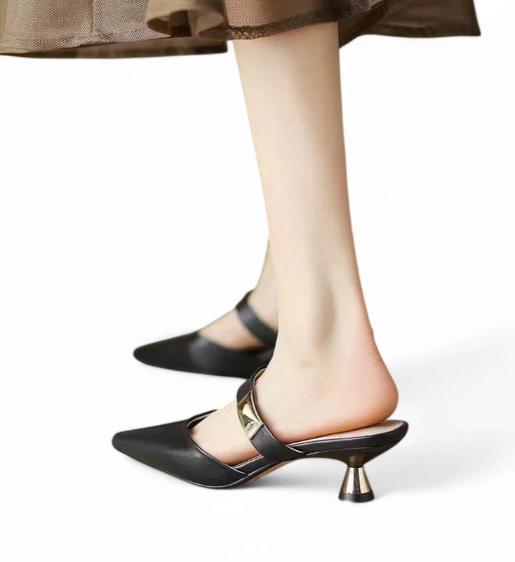 Black mule with wide gold strap, side angle highlighting the shoe’s lines and flared heel.