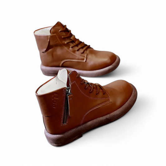 Pair of brown leather ankle boots with flat heel and rubber sole on white background.

