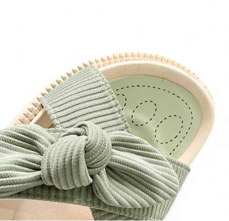 Zoomed view of ribbed sage-green fabric bow and padded footbed stitching.
