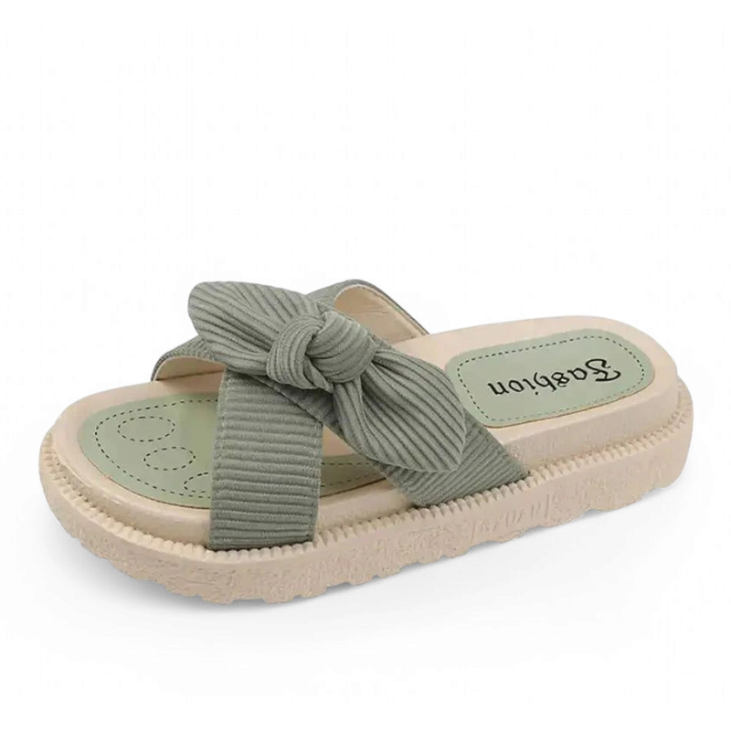 Sage-green slide sandal with knotted strap on a cream EVA platform.