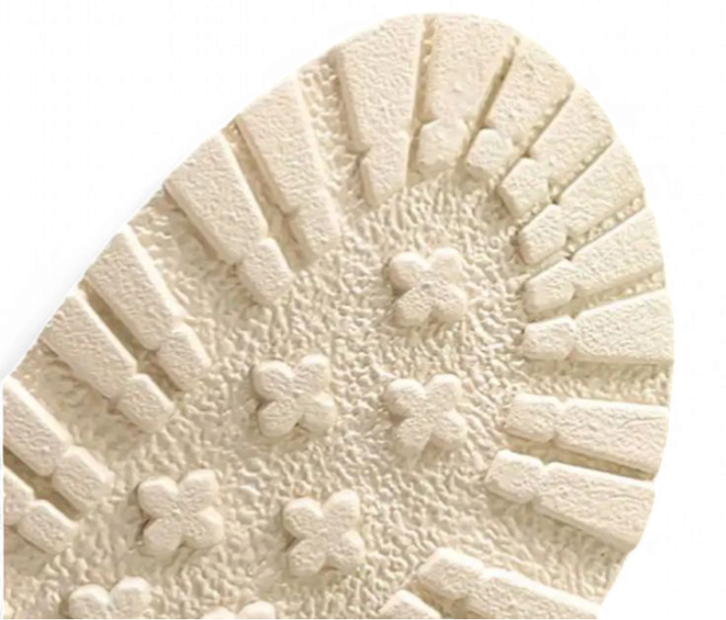 Detail of cream rubber outsole with tiny flower lugs and deep anti-slip grooves.