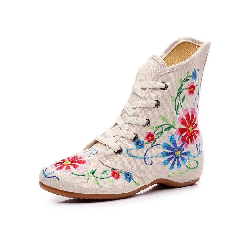 Single beige boot with vivid floral embroidery on white background, round toe.
