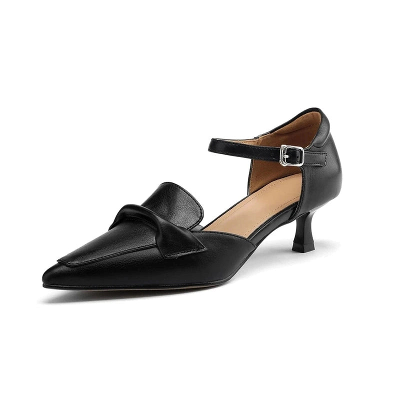 Studio image of black pointed-toe pump with silver buckle ankle strap and flared kitten heel.