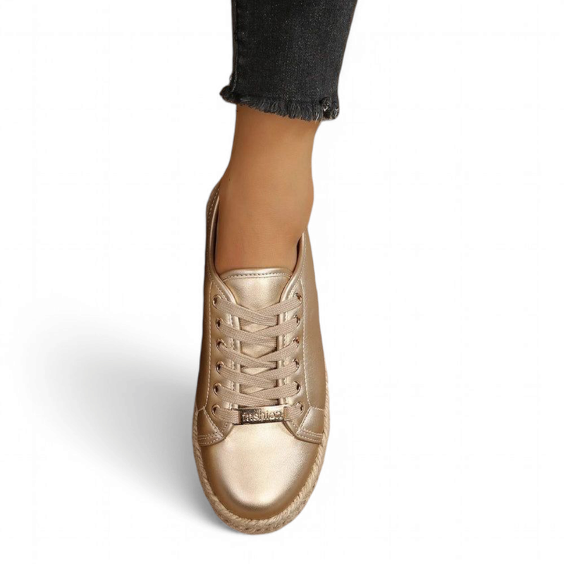 Top-down shot of a gold metallic sneaker with matching laces and braided jute sole.

