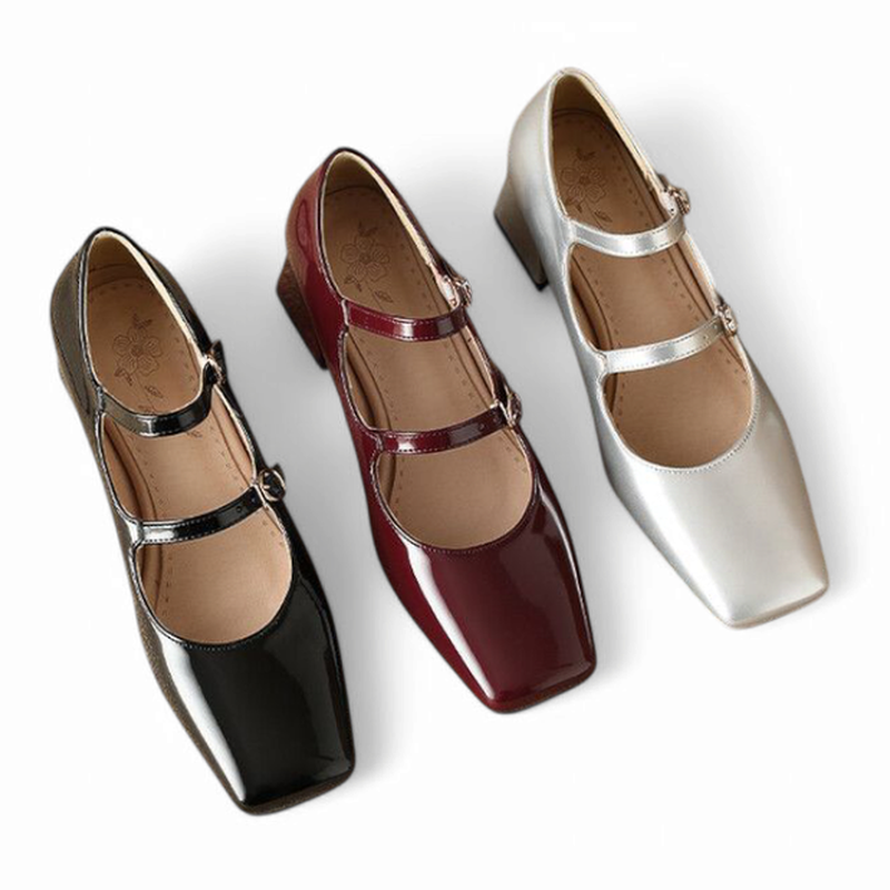 Three glossy Mary Jane pumps in black, burgundy and silver arranged side by side in a top view