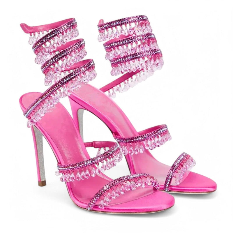 Pair of hot‑pink wrap sandals with tiered crystal straps, angled view