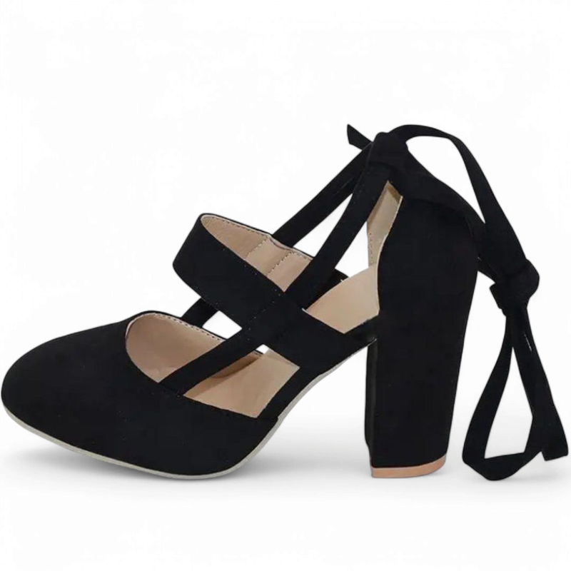 Side view of black faux-suede pump with round toe, chunky heel and ribbon-tie ankle straps.
