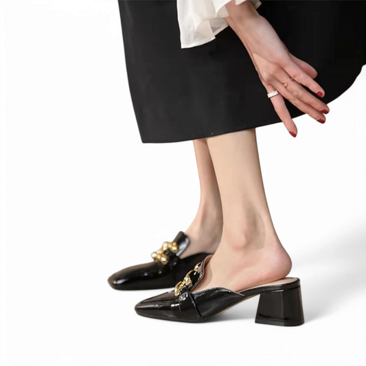 Glossy black mid‑heel mules styled with a black skirt