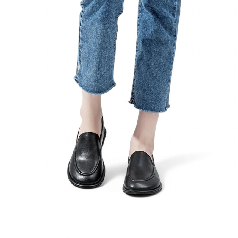 Black leather loafers seen from the front on feet in jeans