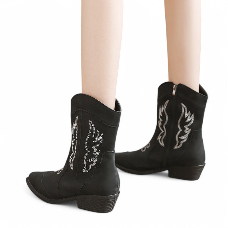 Side-back angle of black Merendy Randa boots worn by a model, highlighting the embroidery and structured heel.
