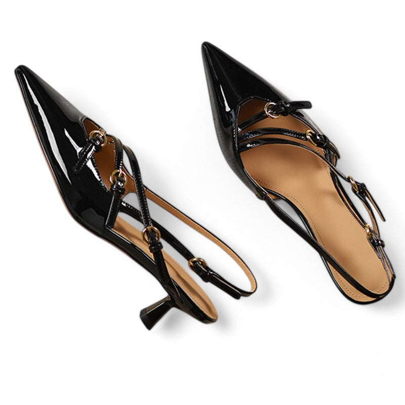 Flat-lay of black patent pumps showing pointed toes and slim heel.