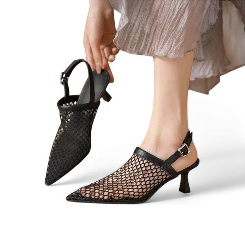 Black mesh version on foot while the other shoe is held in hand, highlighting buckle strap and balanced heel.
