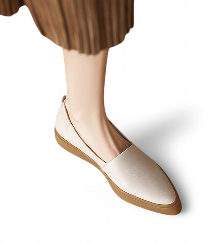 Model wearing a cream‑beige pointed‑toe loafer with tan sole, side view