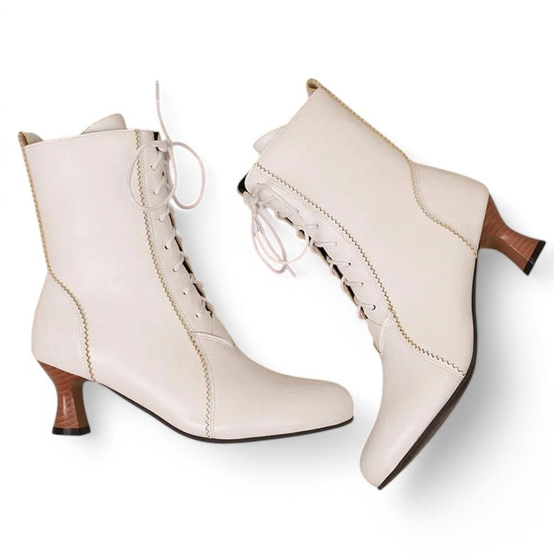 Both Merendy Samira Victorian boots are lying flat on a white surface. The image shows a relaxed top view angle, highlighting the lace-up fronts, rounded toes, and square heels in a soft resting position.