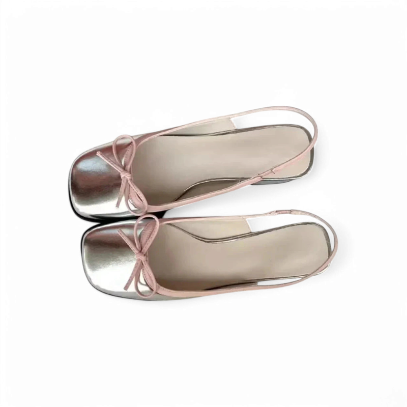 Top view of silver square-toe slingback ballet flats with pink trim and bow, pair aligned heel to toe on white background.	