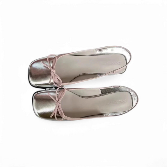 Top view of silver slingback pair placed parallel with pink edging visible