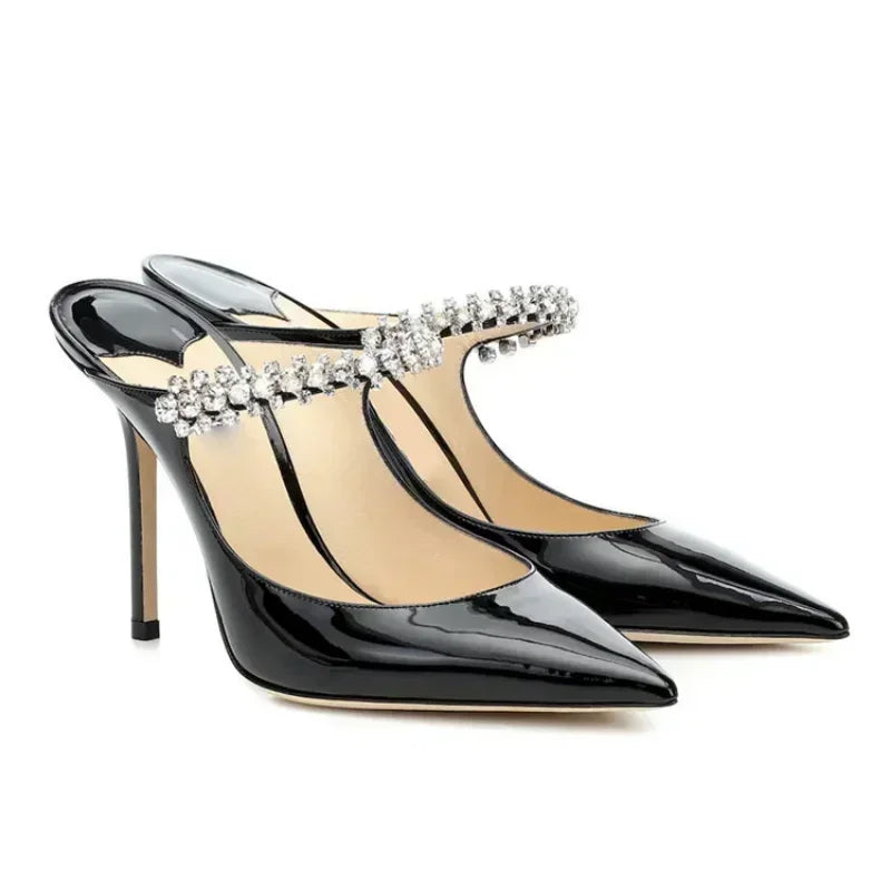 Pair of black patent leather mules with crystal straps, angled front view