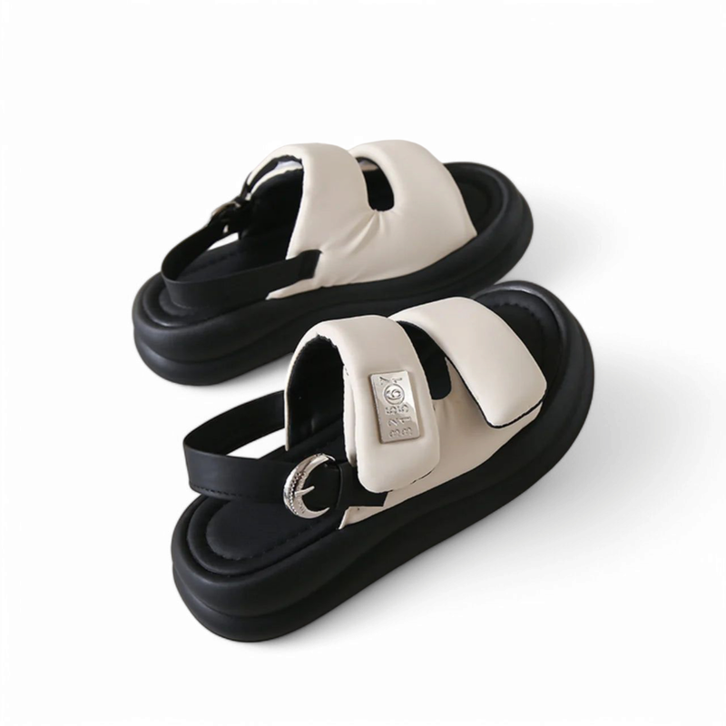 Pair of cream padded slingback sandals with metal buckle and black flatform sole, angled pair view.