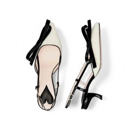 Flat-lay and side angle of the same shoe highlighting the pointed toe, ivory-black contrast, front bow, and slim kitten heel.