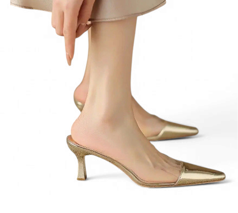 Gold pointed mule on foot, highlighting mid-height heel and clear PVC panel.