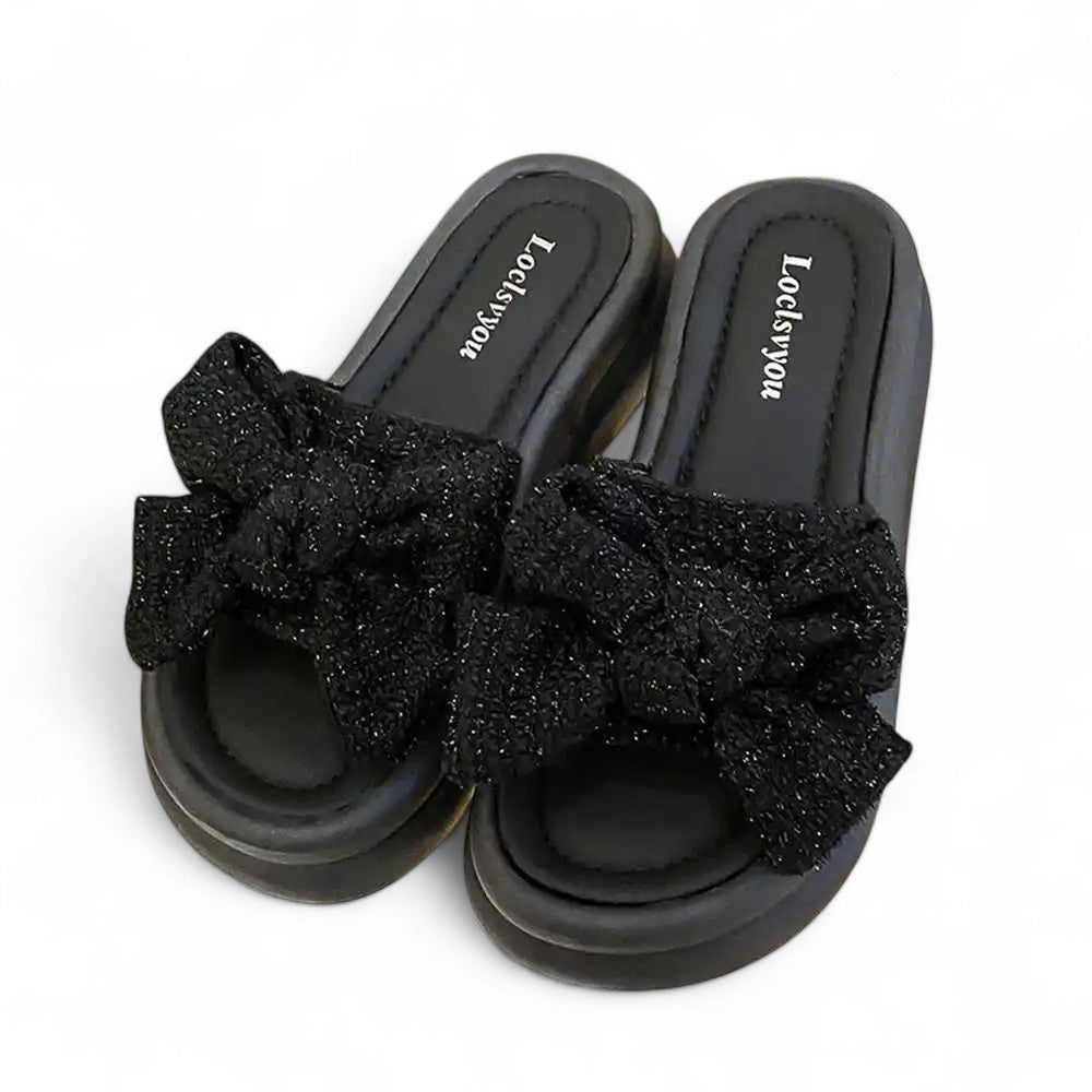 Black sandals with glittery bows on a white background