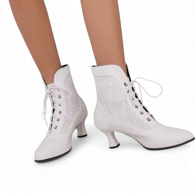 A pair of white Victorian-style ankle boots with lace-up design and kitten heels, worn by a woman standing on a white background.