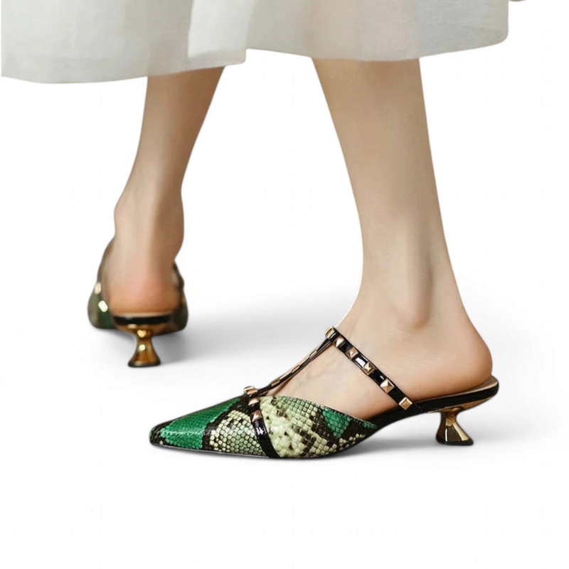 Green python-pattern kitten-heel mule with studded T-strap, shown on walking model, white backdrop