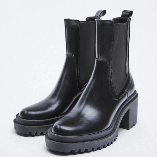 Both boots shown in a glossy black finish from a dual angle, capturing the front curve and chunky heel structure.

