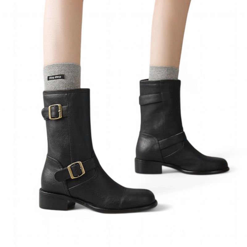 A woman wearing the Merendy wide-calf boot in black.the rounded toe, ankle strap with metal buckle, and mid-height square heel are clearly visible. The boot fits comfortably around the calf and complements a casual outfit.