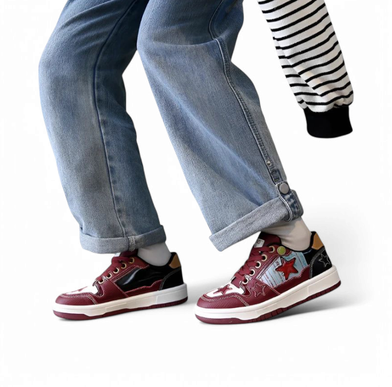 Low-top wine red sneaker with embroidered stars and flat white sole, side profile.

