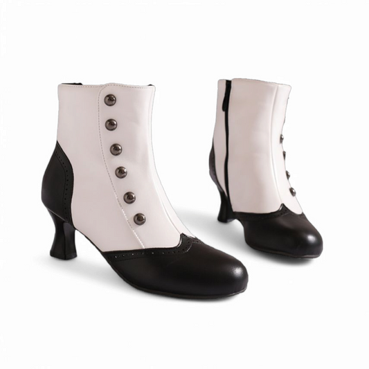A front angled view showing a pair of Victorian-style ankle boots in black and white with metal button detailing, round toes, and kitten square heels.