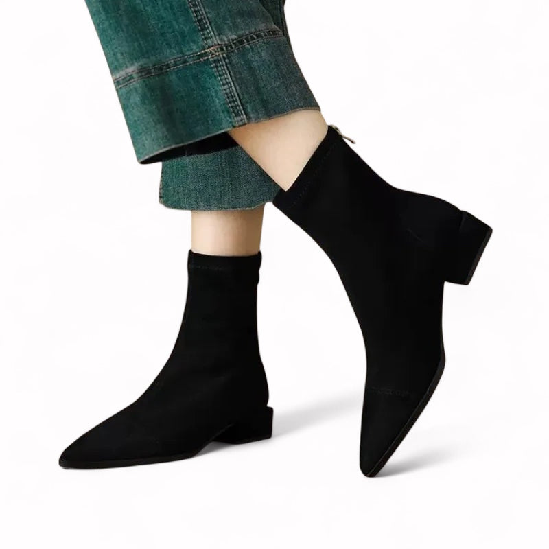 Black sock boots worn with green jeans on a white background