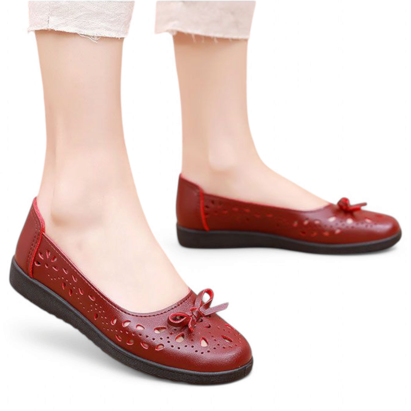 Red round-toe ballet flat with same perforations and bow, on-foot side angle.