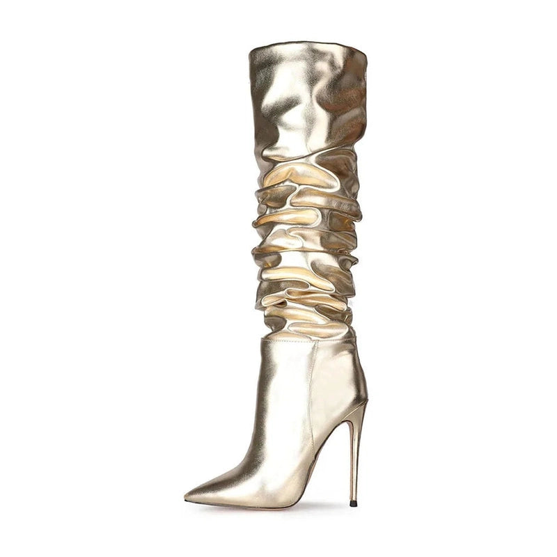 Gold knee-high boot with ruched shaft, thin stiletto heel and pointed toe, side view.

