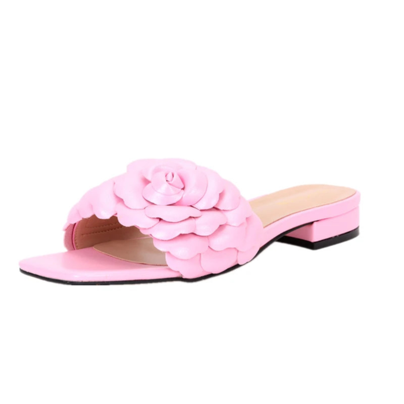 Light-pink leather slide lying in profile, showing layered petals on strap.