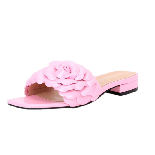 Light-pink leather slide lying in profile, showing layered petals on strap.