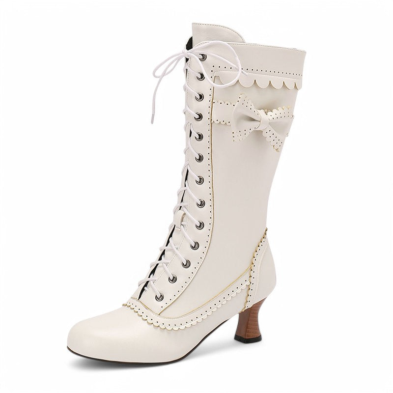 Side profile of a single Victorian-style boot with scalloped edges, lace-up front, and decorative bow, shown in white.