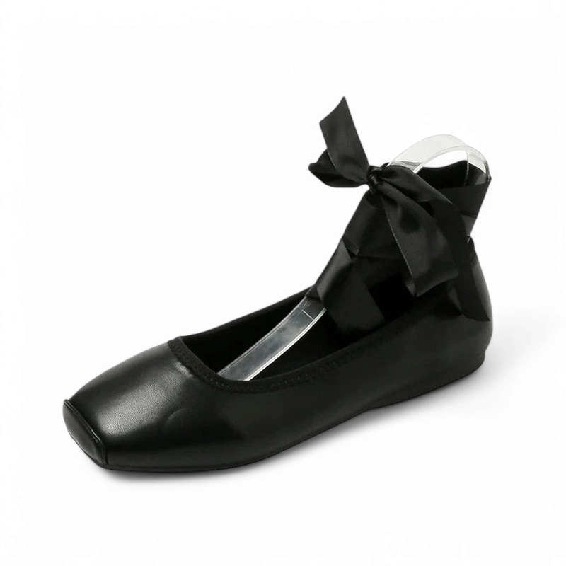 Black square-toe flat with satin bow tied at ankle.

