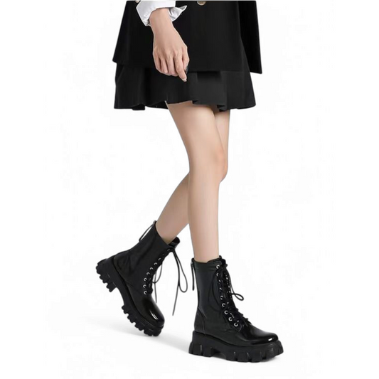 A woman walking in the boots while wearing a short black dress.