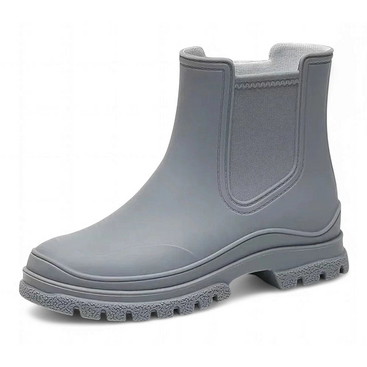 Close-up side view of a single grey Chelsea boot with thick sole and elastic side panel.
