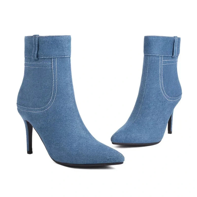 Pair of mid-wash blue denim ankle boots with pointed toes and slim black heels.