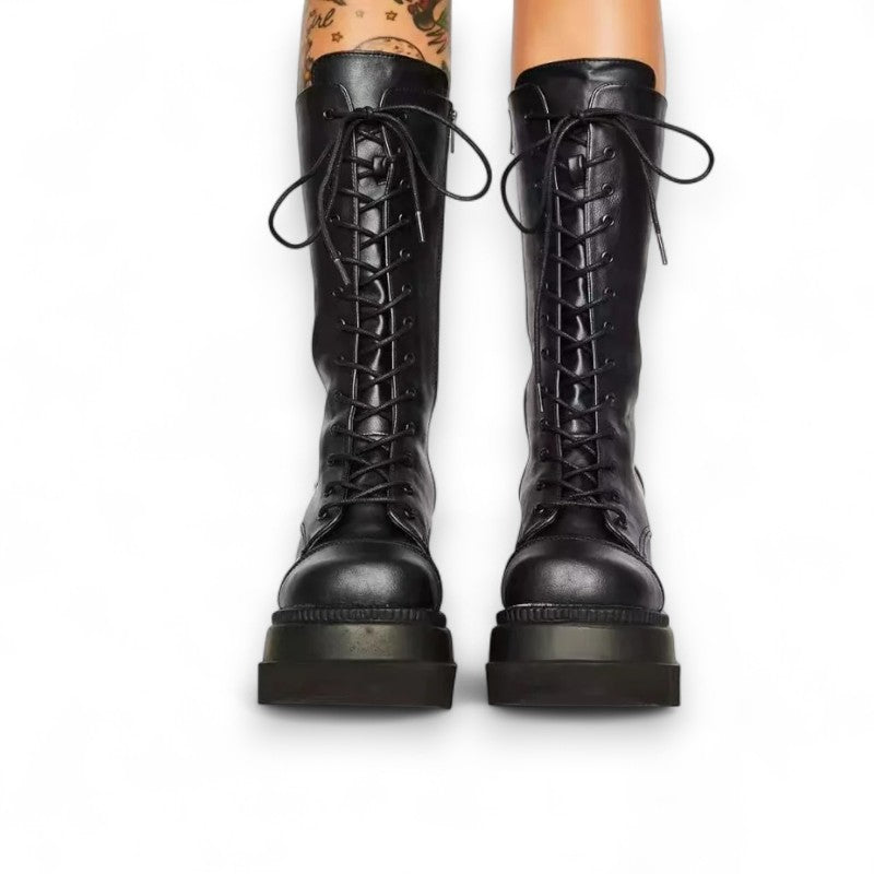 Front view of a pair of tall black platform boots with laces tied.