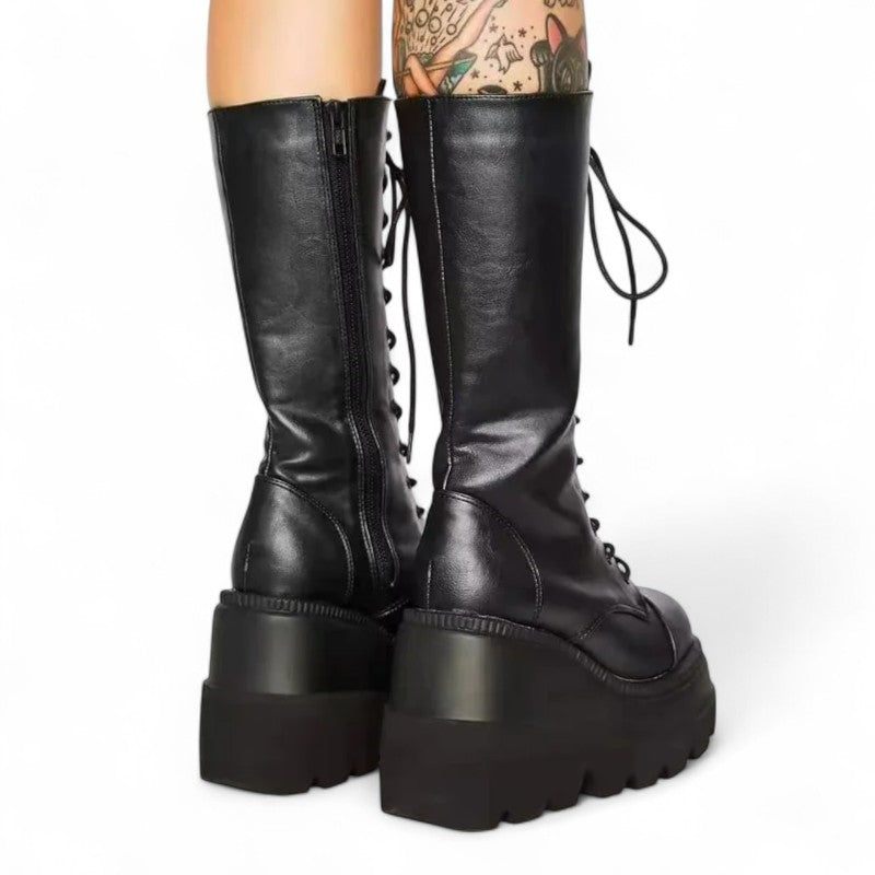 Rear angled view of tall black platform boots showing wedge heel.